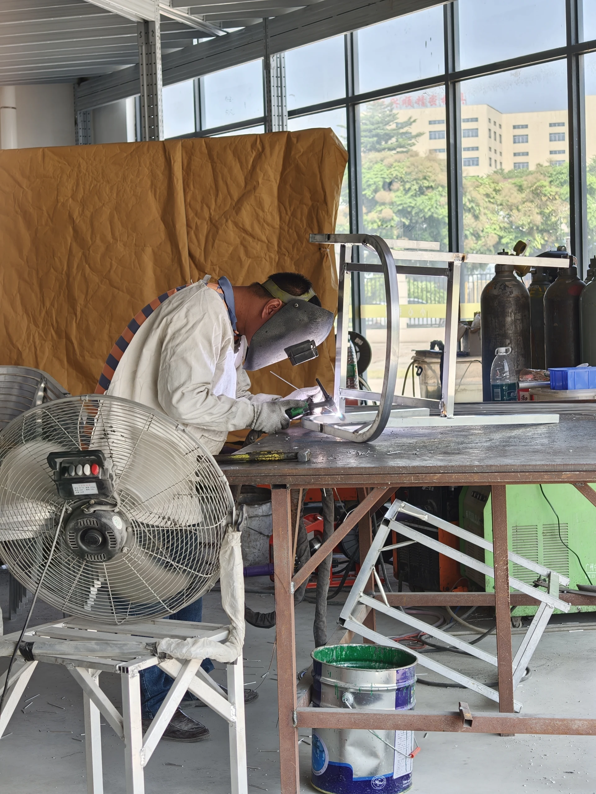 Welding a chair frame at the workbench.