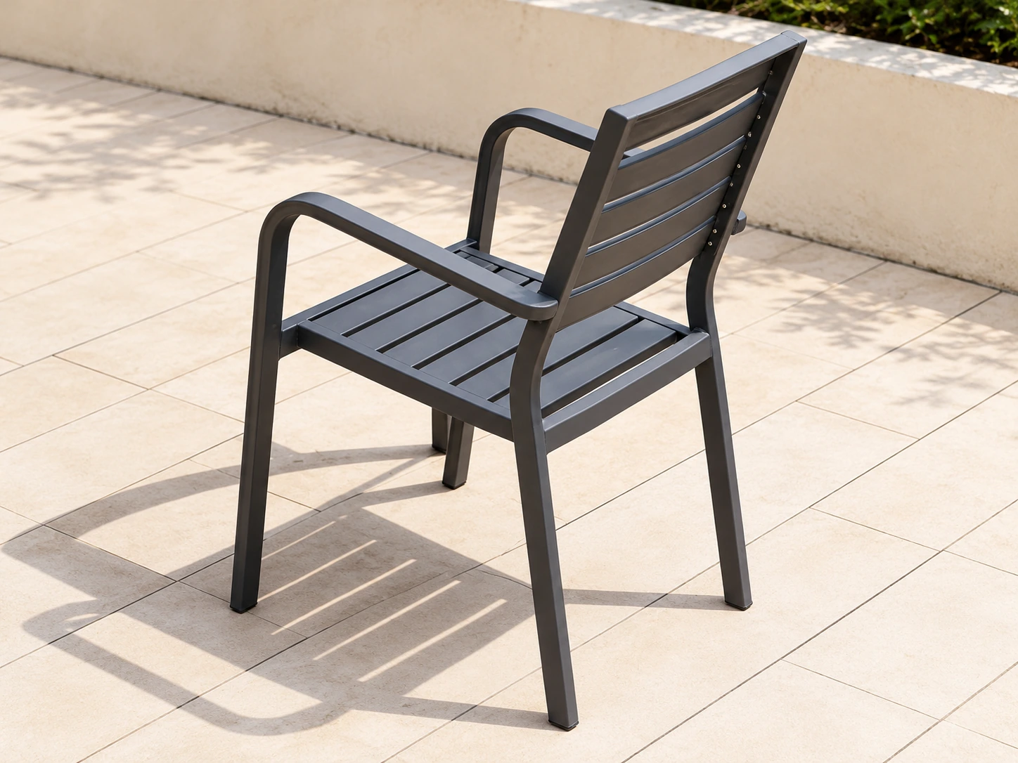 Single grey outdoor armchair with horizontal slatted seat and back, viewed from the rear
