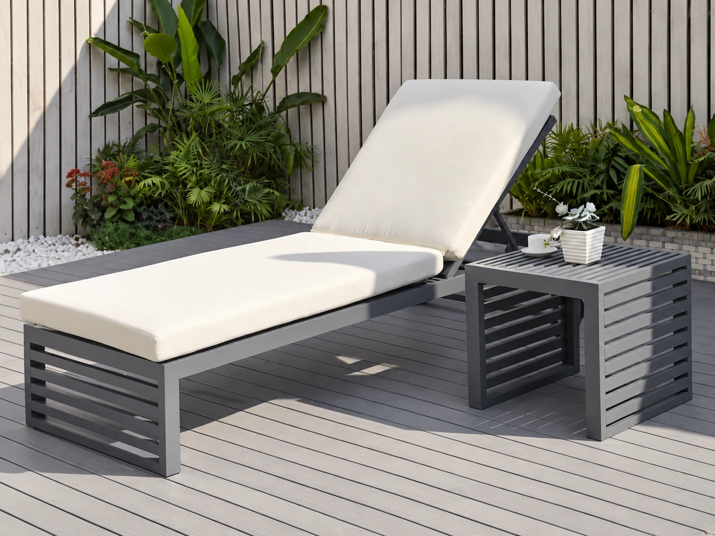Dark grey cushioned sun lounger with a matching slatted side table